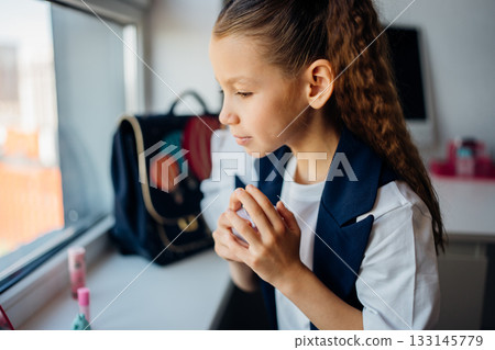 Young girl applying makeup in bright room near window 133145779