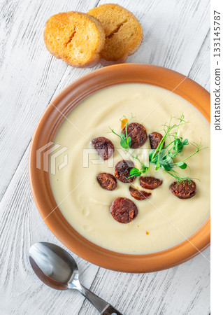 Terracotta bowl of creamy cauliflower soup paired with toasted baguette on bright wooden surface Terracotta bowl of creamy cauliflower soup paired with toasted baguette on bright wooden surface 133145787