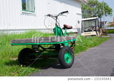 Flatbed moped parked on street of the peaceaful car-free Vrango island with seaside village in Gothenburg archipelago, Vrango, Sweden 133145841