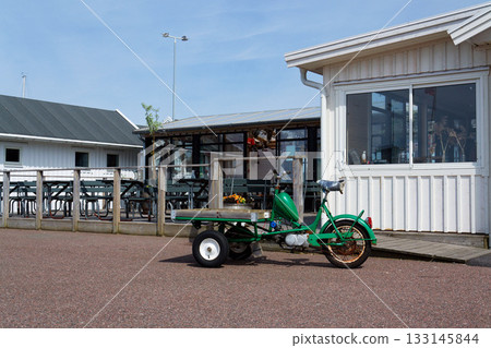 Flatbed moped parked on street of the peaceaful car-free Vrango island with seaside village in Gothenburg archipelago, Vrango, Sweden 133145844