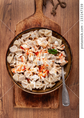 Traditional Turkish dumplings served with yogurt and spicy sauce on a green decorative plate 133147339