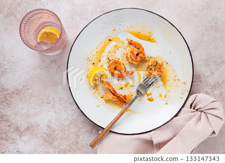 the remains of fried shrimp in oil with spices, on a white plate, with a fork, there are no people, 133147343
