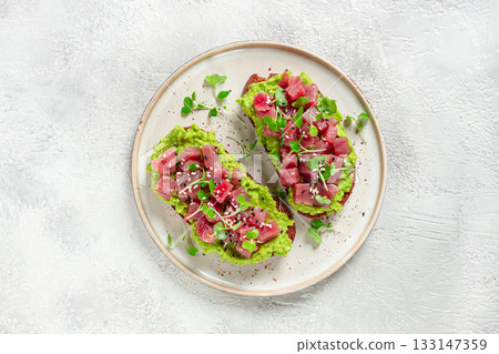 toasts with fresh tuna and avocado, spread on black bread and sprinkled with microgreens, breakfast, healthy food toasts with fresh tuna and avocado, spread on black bread and sprinkled with microgreens, breakfast, healthy food 133147359