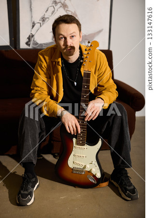 Guitarist ready pose, Man prepares guitar with confidence 133147616