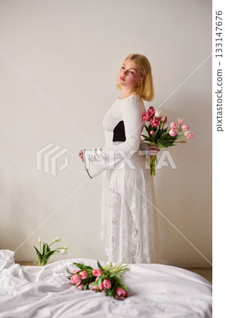 Stylish blonde offers colorful bouquet with welcoming stance Stylish blonde offers colorful bouquet with welcoming stance 133147676