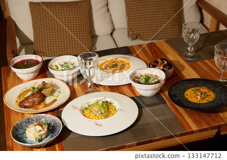 A Variety of Assorted Gourmet Dishes Displayed on a Beautiful Wooden Table Setting for Dining 133147712