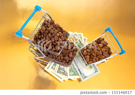 small shopping cart filled with roasted coffee beans sits on a golden surface 133148017