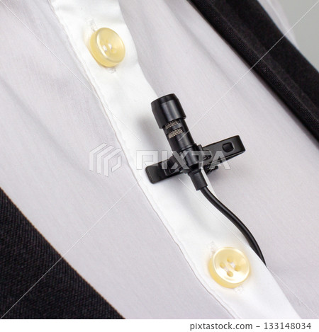 lav mic is secured on a white buttoned shirt, capturing the setup for professional audio recording. lav mic is secured on a white buttoned shirt, capturing the setup for professional audio recording. 133148034