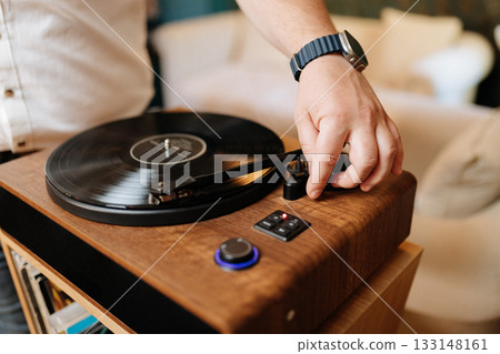 Hand lowering tonearm on vinyl record player, cozy home audio setup Hand lowering tonearm on vinyl record player, cozy home audio setup 133148161