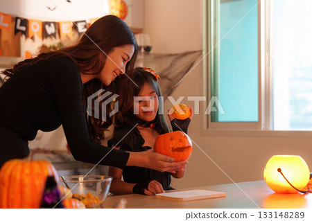 Halloween Pumpkin Fun. Mother and daughter showcasing their carved pumpkin. 133148289