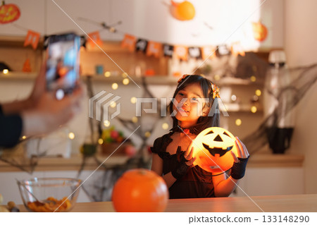 Halloween Portrait. Child posing with a glowing pumpkin for a photo. 133148290