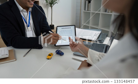 Insurance Consultation. Businessman explaining terms to client with document and toy cars. Insurance Consultation. Businessman explaining terms to client with document and toy cars. 133148457