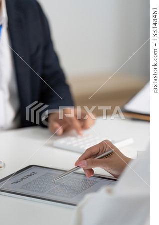 Financial Review. Businessman and client analyzing insurance document on tablet. Financial Review. Businessman and client analyzing insurance document on tablet. 133148461