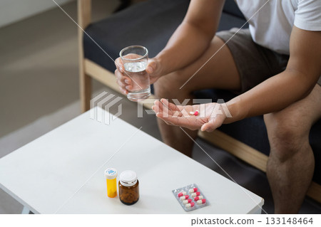 Medication Management. Individual preparing to take pills with water at home. 133148464