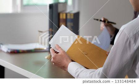 Document Review. A client holding a legal envelope while consulting with a lawyer. 133148484