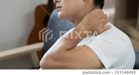 Health. Young man experiencing neck pain and discomfort at home. Health. Young man experiencing neck pain and discomfort at home. 133148493