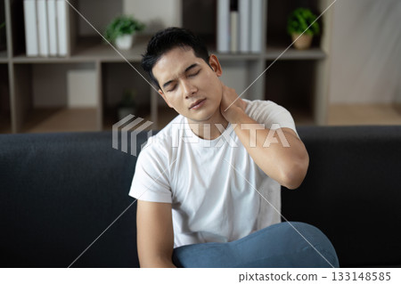 Neck Pain Relief. Man rubbing neck in discomfort while seated. 133148585