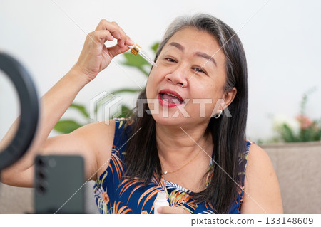 Skincare routine. Mature woman applying serum on her face. 133148609