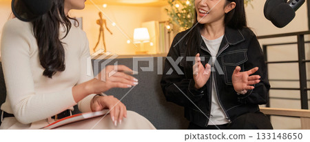 Dynamic Dialogue. Two women sharing ideas in a podcast studio setting. 133148650
