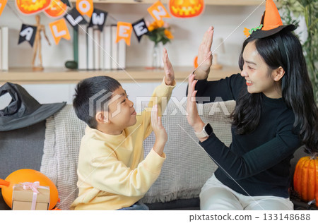 Halloween Celebration. A joyful mother and son playing together in festive costumes. Halloween Celebration. A joyful mother and son playing together in festive costumes. 133148688