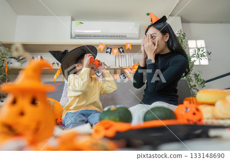 Halloween Spirit. A mother and son enjoying playful interactions with festive props. 133148690
