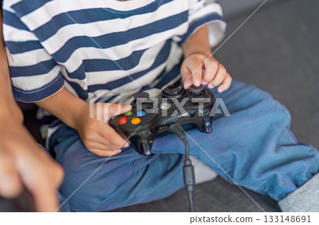 Gaming Fun. Child holding a video game controller, engaged in play. Gaming Fun. Child holding a video game controller, engaged in play. 133148691
