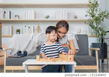 Creative Play. Mother and son engaging with wooden toys at home. Creative Play. Mother and son engaging with wooden toys at home. 133148697