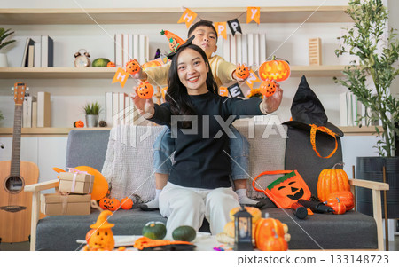 Halloween Celebration. A joyful woman and child surrounded by festive decorations and pumpkins. Halloween Celebration. A joyful woman and child surrounded by festive decorations and pumpkins. 133148723