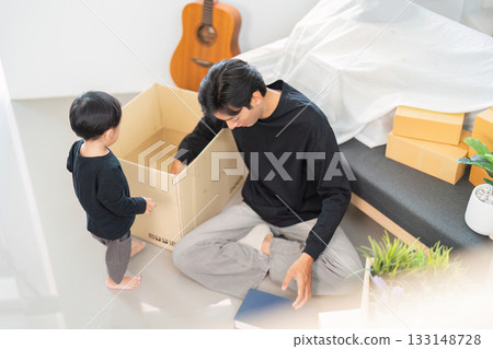Father and son engaging in playful unpacking at home 133148728