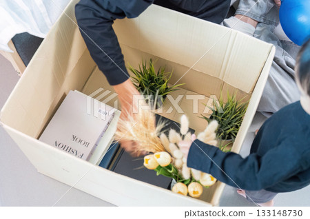 Family Bonding. Parent and child unpacking boxes together in a cozy home environment. 133148730