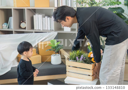 Father and child bonding while unpacking flowers at home 133148810