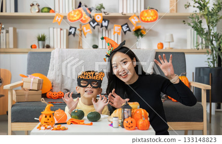 Halloween Celebration. Joyful mother and child decorating pumpkins at home. Halloween Celebration. Joyful mother and child decorating pumpkins at home. 133148823