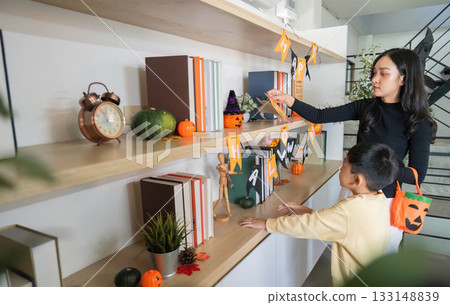 Halloween Celebration. A mother and son decorating their home with festive Halloween decorations. 133148839