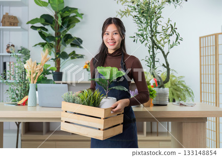 Plant Shop. Woman carrying a wooden crate filled with various plants. Plant Shop. Woman carrying a wooden crate filled with various plants. 133148854