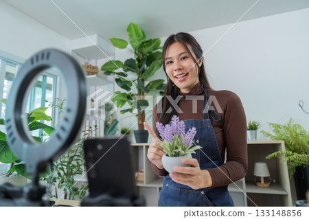 Social Media. Young woman presenting a plant in front of a camera for online content. 133148856