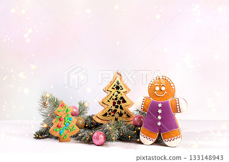 Festive winter greeting card and banner on the screen, New Year's gingerbread and Christmas decorations on snowy fir branches, Christmas and New Year's background with lights and decorations 133148943
