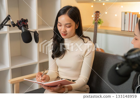 Podcast Preparation. Woman taking notes during a creative discussion in a studio. Podcast Preparation. Woman taking notes during a creative discussion in a studio. 133148959