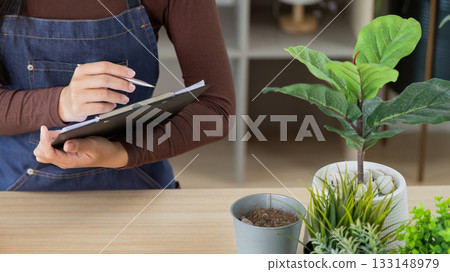 Floral Business Owner Taking Notes in a Green Workspace Floral Business Owner Taking Notes in a Green Workspace 133148979