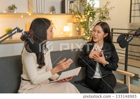 Podcast Recording Session. Two women animatedly discussing topics on a couch. Podcast Recording Session. Two women animatedly discussing topics on a couch. 133148985