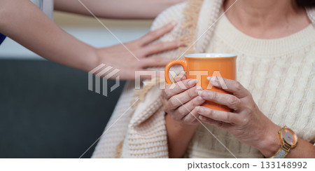 Supportive Care. Nurse offering warm beverage to elderly woman, enhancing comfort. 133148992