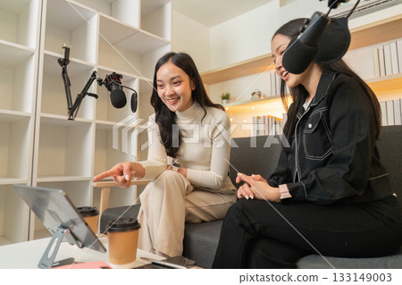Podcasting. Two women engaged in a lively conversation while recording. 133149003