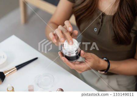 Skincare Routine. Woman applying cream from jar on her hand at home. 133149011