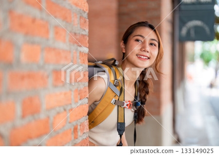 Travel. Young woman exploring city with backpack and camera, enjoying adventure. 133149025