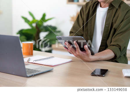 Work from Home: Individual using tablet while managing tasks at home 133149038