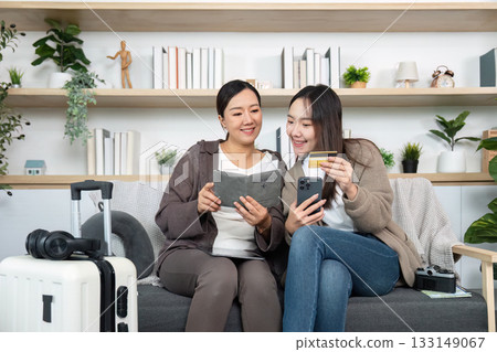 Mother and Daughter Enjoying Quality Time. A mother and daughter reading together while planning a trip. 133149067
