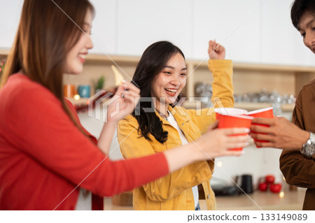 Exciting party moment with friends raising cups in celebration 133149089