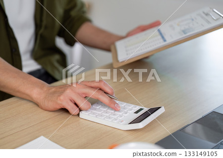 Working from Home. Focused Professional Using Calculator for Financial Planning Working from Home. Focused Professional Using Calculator for Financial Planning 133149105