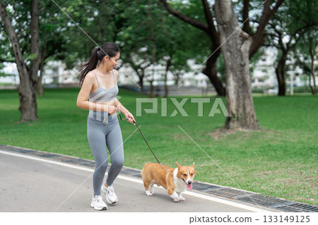 Wellness and Fitness. Woman enjoying a walk with her corgi in a park. Wellness and Fitness. Woman enjoying a walk with her corgi in a park. 133149125