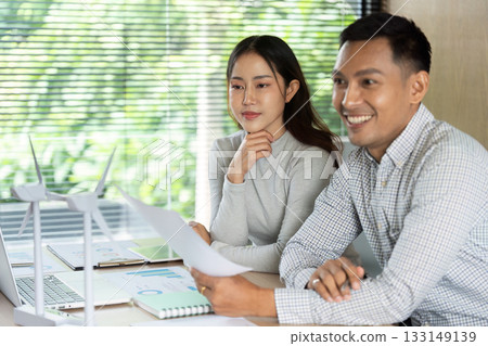 Sustainable Innovation. Professionals reviewing eco-friendly project plans at a workspace. Sustainable Innovation. Professionals reviewing eco-friendly project plans at a workspace. 133149139