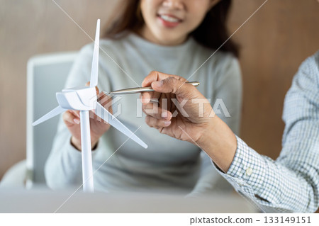 Sustainable Energy Discussion. Team examining a wind turbine model in a collaborative setting. Sustainable Energy Discussion. Team examining a wind turbine model in a collaborative setting. 133149151